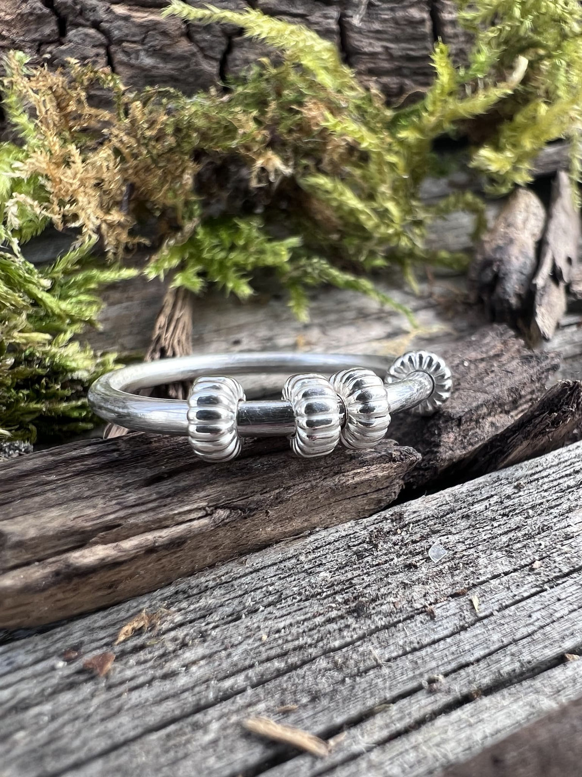 Recycled sterling silver corrugated spinner ring on mossy driftwood, handmade anxiety ring Isle of Wight