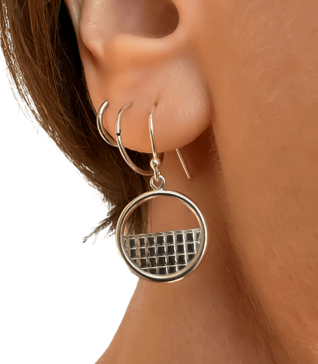 Sterling silver lattice halo earrings worn in ear, showing the circular lattice pendant scale and drop length