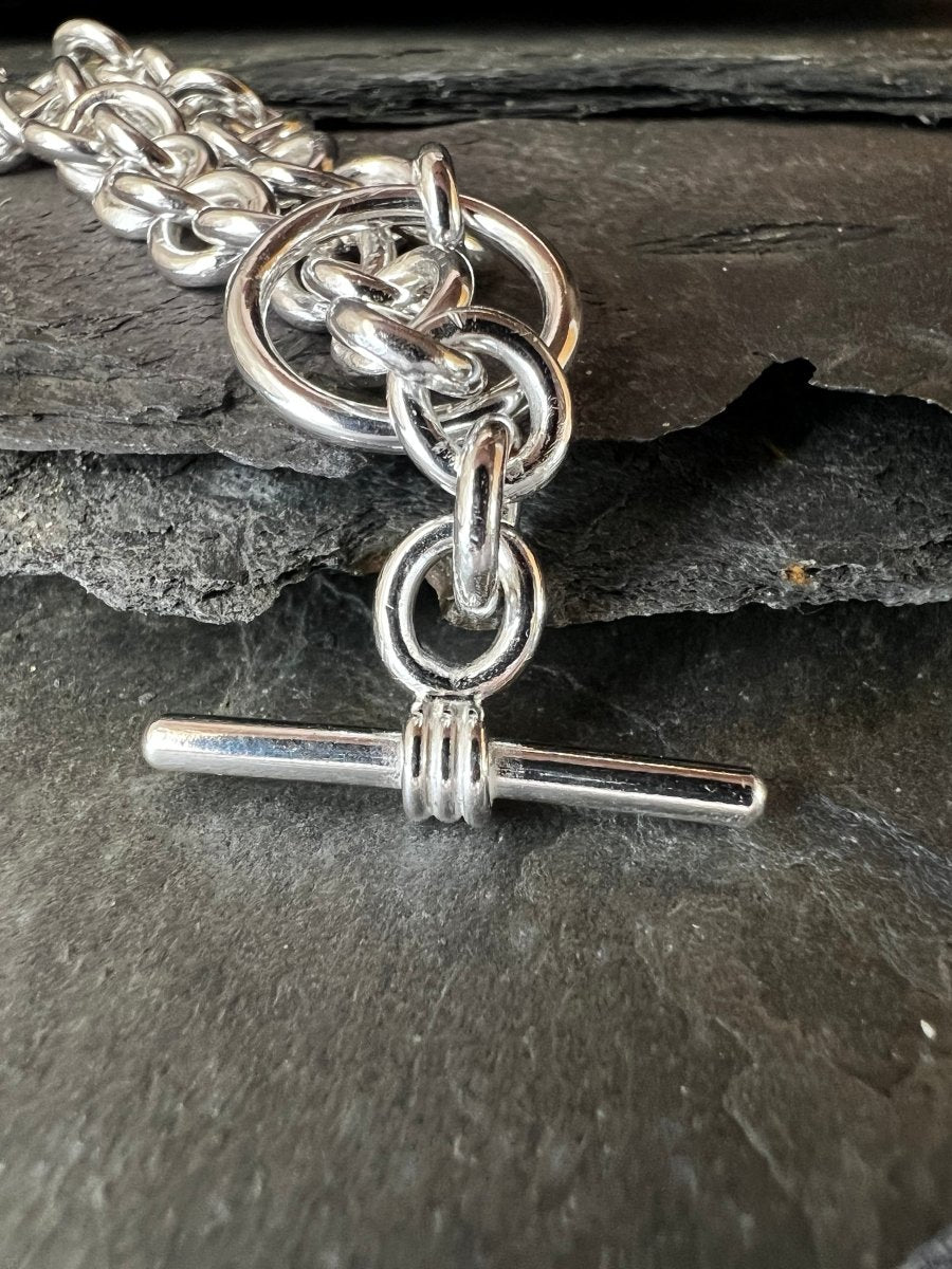 Silver chain bracelet with a toggle clasp on a dark stone surface