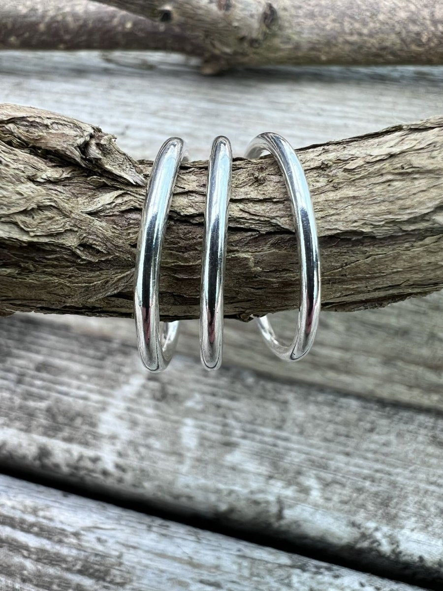Thin sterling silver stacking rings hanging from a weathered branch, Isle of Wight handmade jewellery