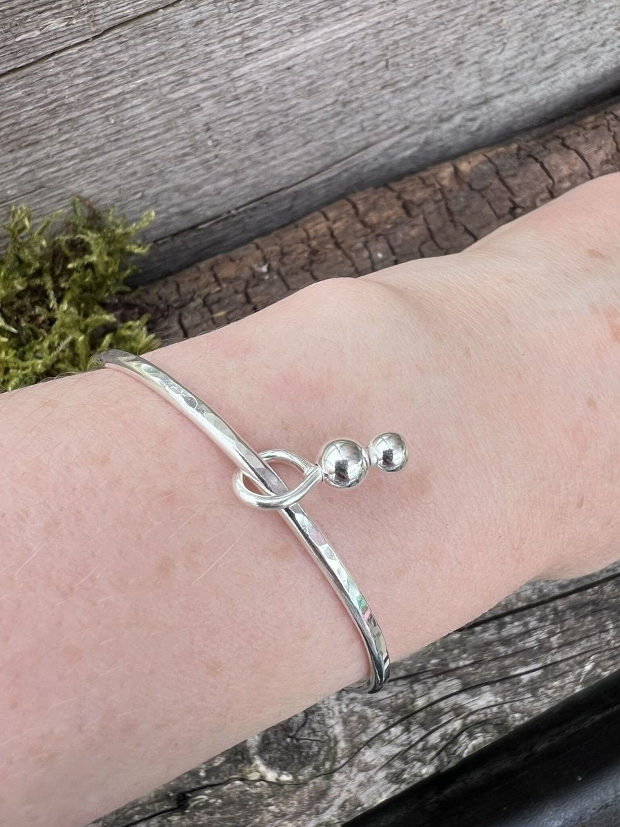 Recycled sterling silver bauble charm bangle worn on a wrist, showing scale and how the bead charms hang
