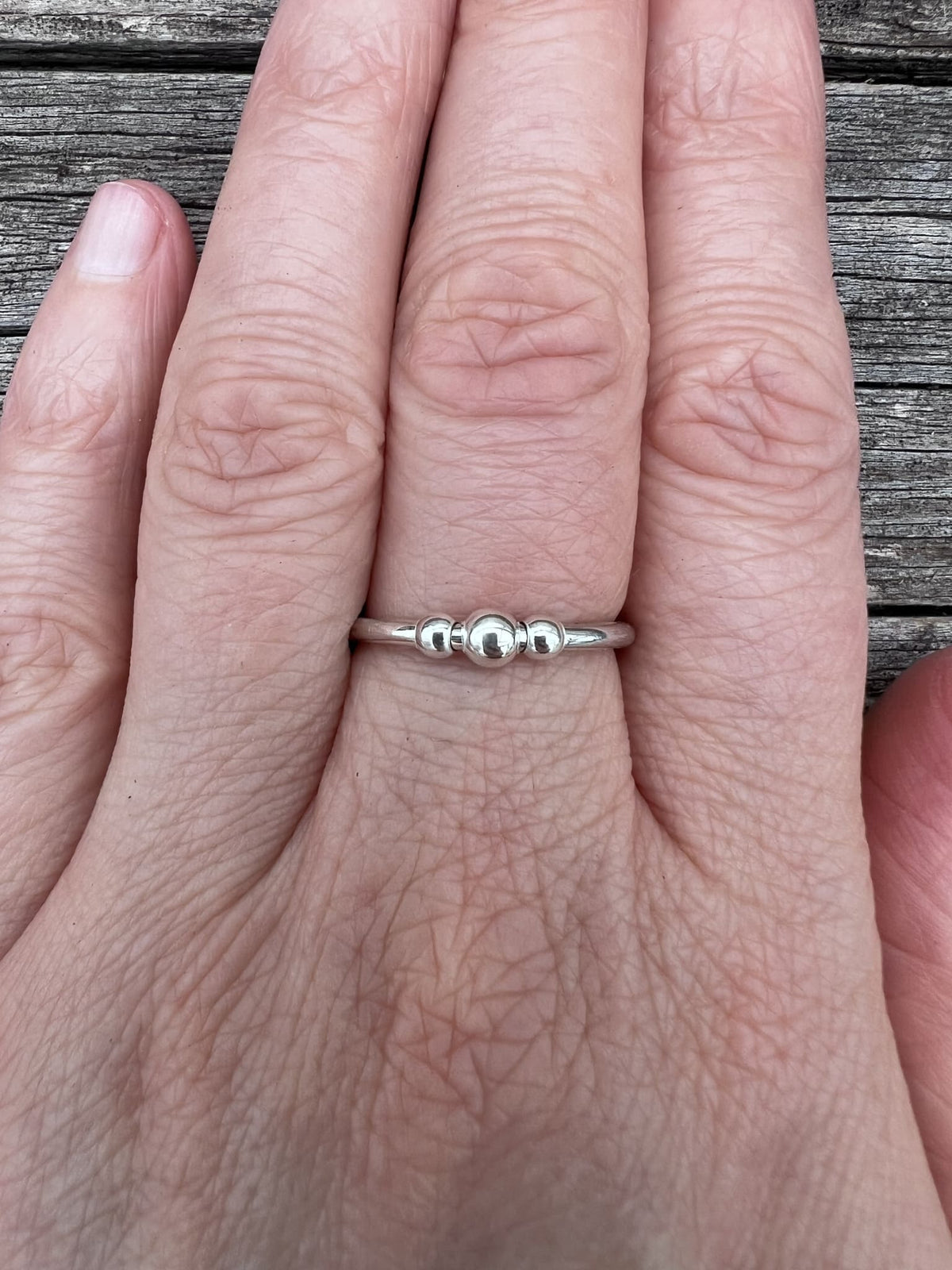 Recycled sterling silver beaded spinner ring worn on a finger, showing the beaded spinning outer band on the hand