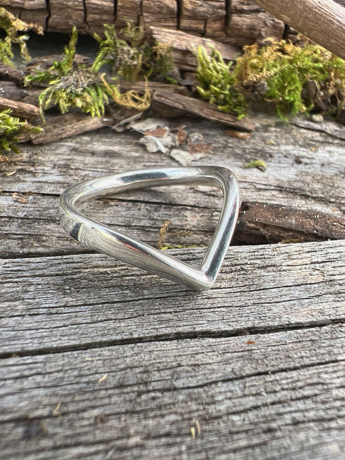 Recycled sterling silver chevron ring on weathered driftwood, showing the V-shaped open geometric band