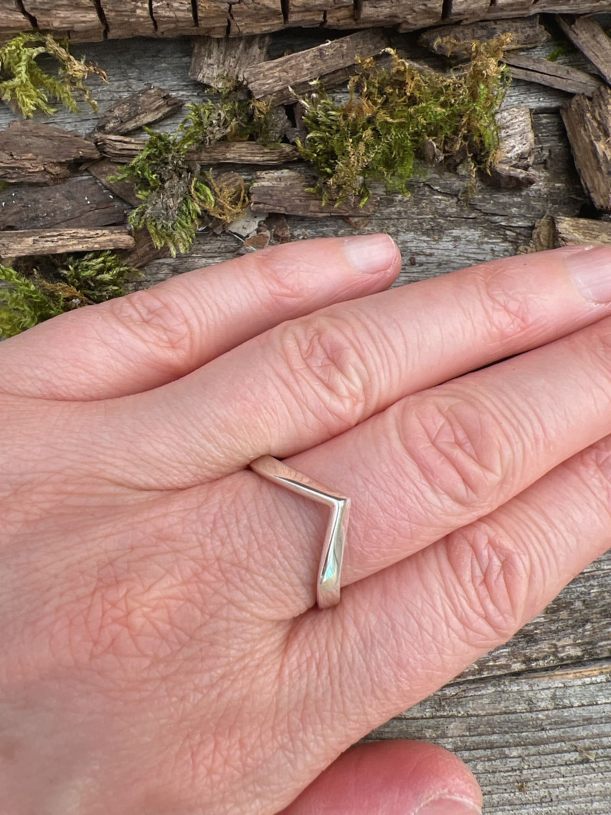 Sterling silver chevron ring worn on finger, showing scale and the open V-shaped geometric band