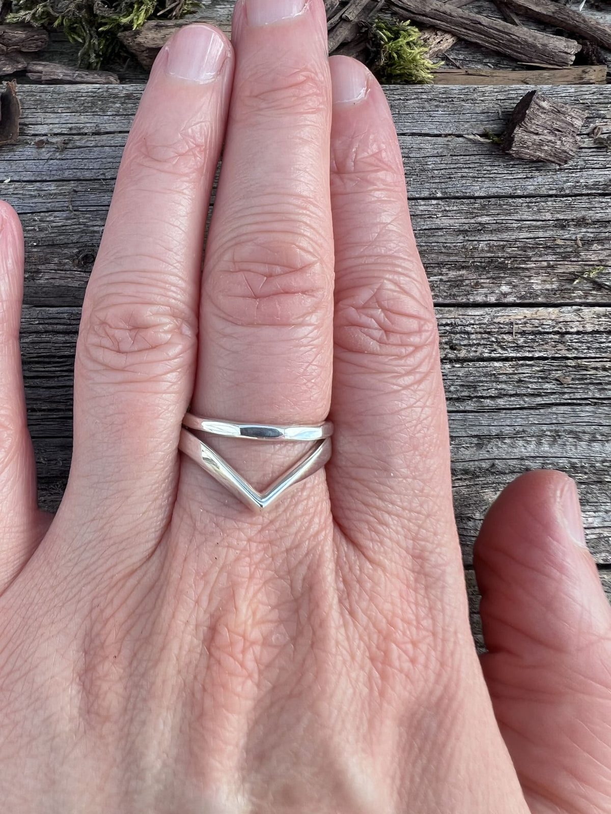 Recycled sterling silver chevron ring worn stacked on a finger, showing the V-shape against another ring