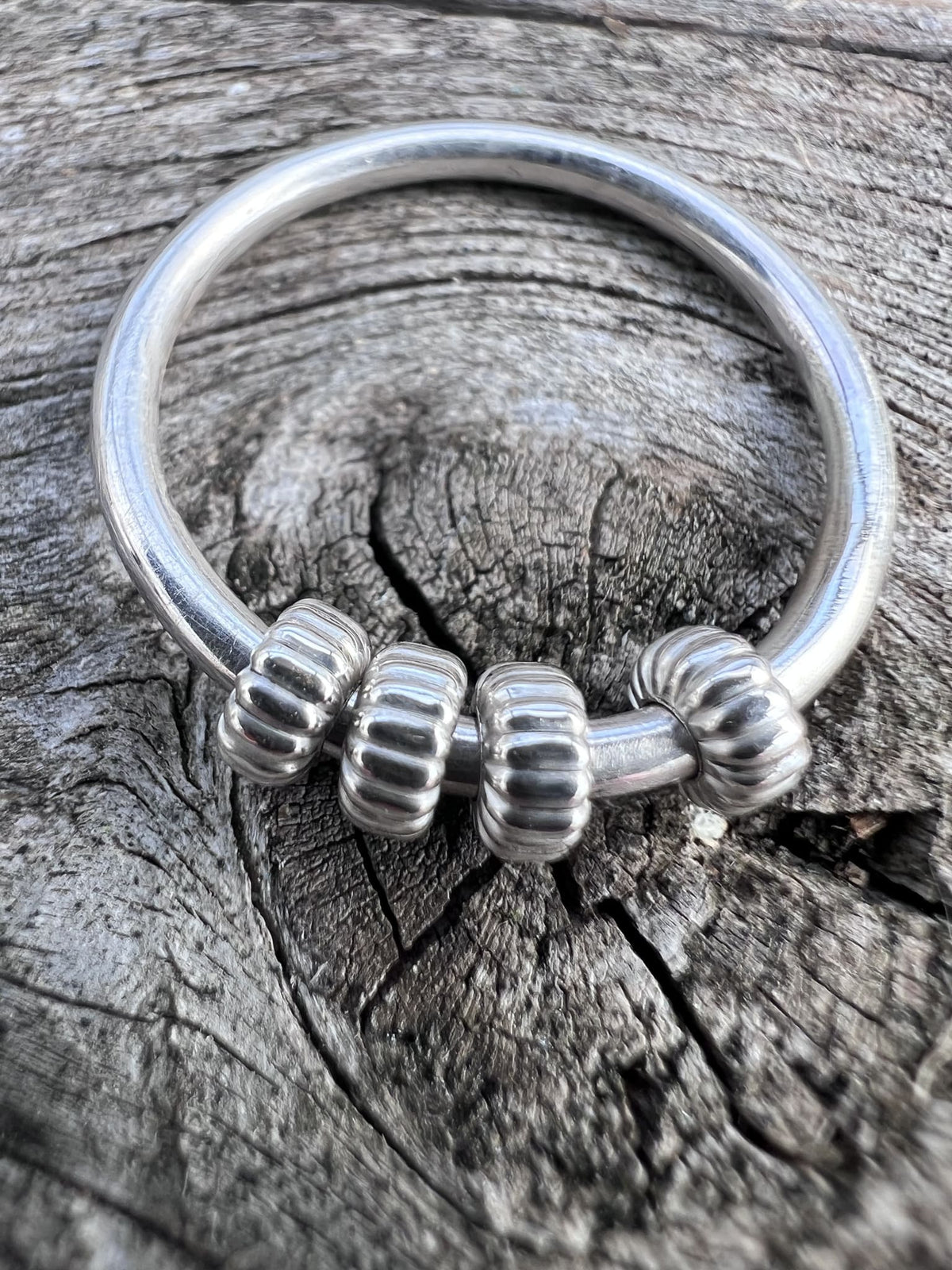 Close-up of a handmade sterling silver corrugated spinner ring, showing the ridged texture on the spinning outer beads