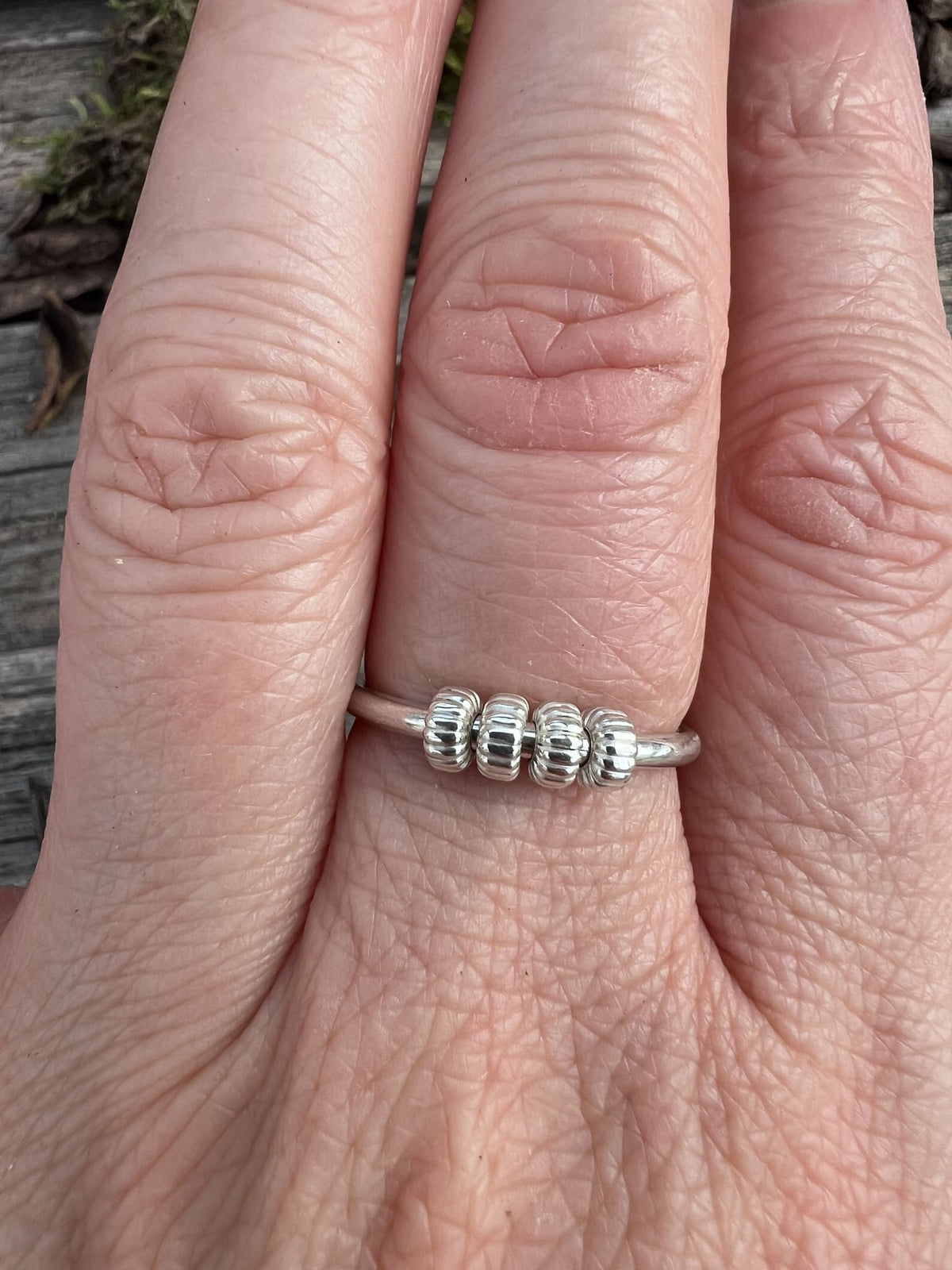Sterling silver corrugated spinner ring worn on a finger, showing scale and the textured spinning outer beads