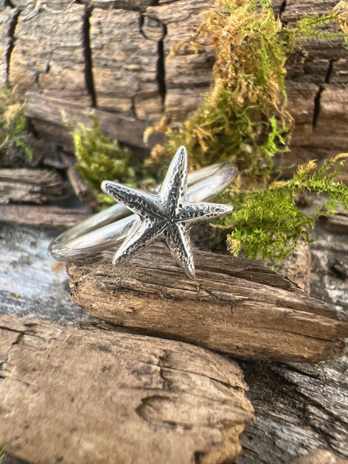 Recycled sterling silver delicate starfish ring on mossy driftwood, handmade coastal jewellery Isle of Wight