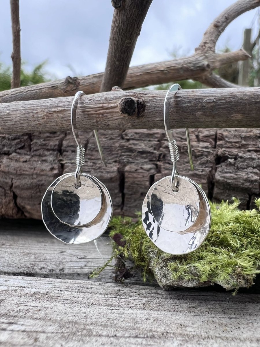Recycled silver double domed drop earrings styled on wooden branch with natural foliage in the background