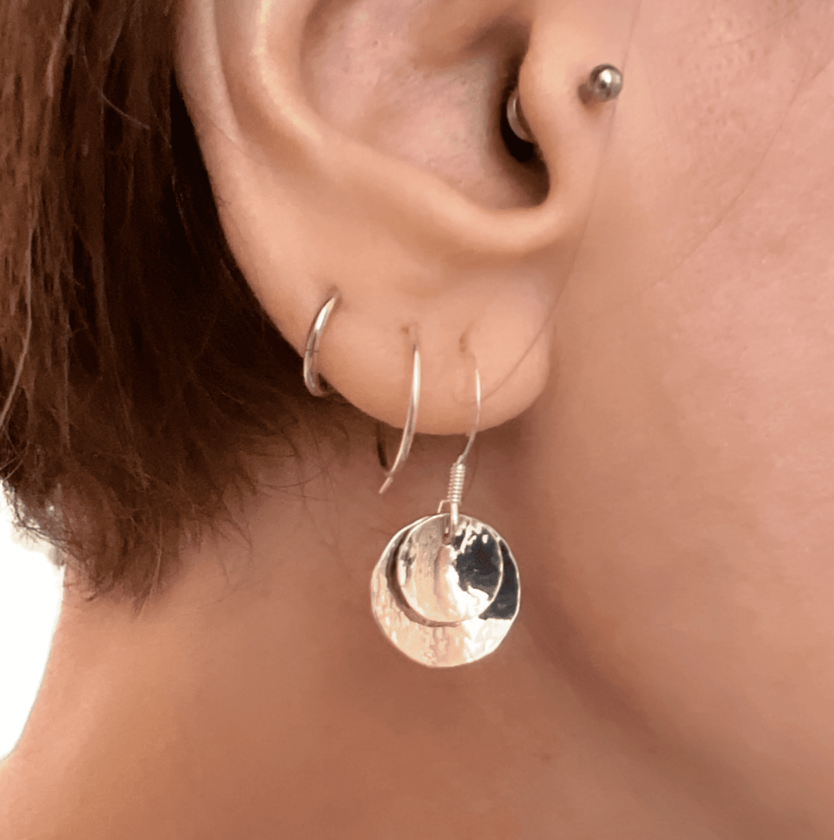 Sterling silver double domed earrings worn in ear, showing the curved disc pendant and drop length against skin