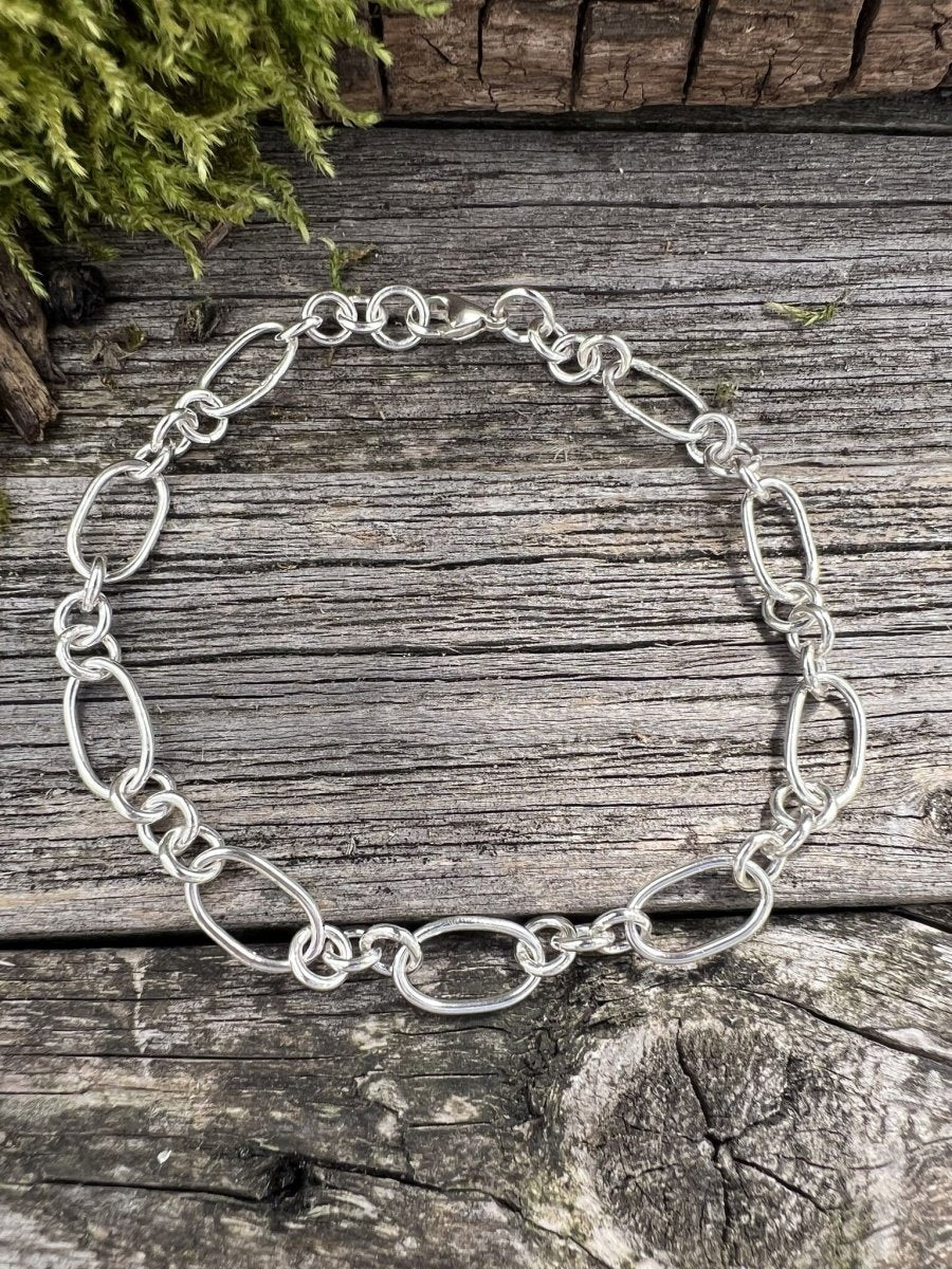 Recycled sterling silver fetter and three link bracelet on weathered wood, showing the mixed oval and round chain links