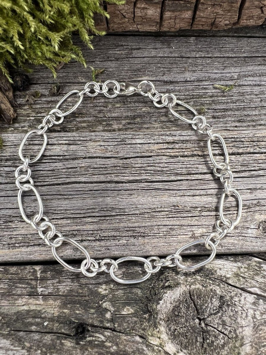 Recycled sterling silver fetter and three link bracelet on weathered wood, showing the mixed oval and round chain links