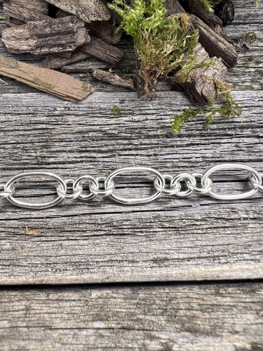 Recycled sterling silver fetter and three link bracelet on weathered wood, showing the alternating chain link design