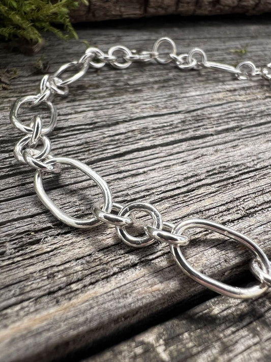 Close-up of a handmade sterling silver fetter and three link bracelet, showing the alternating oval and small round links