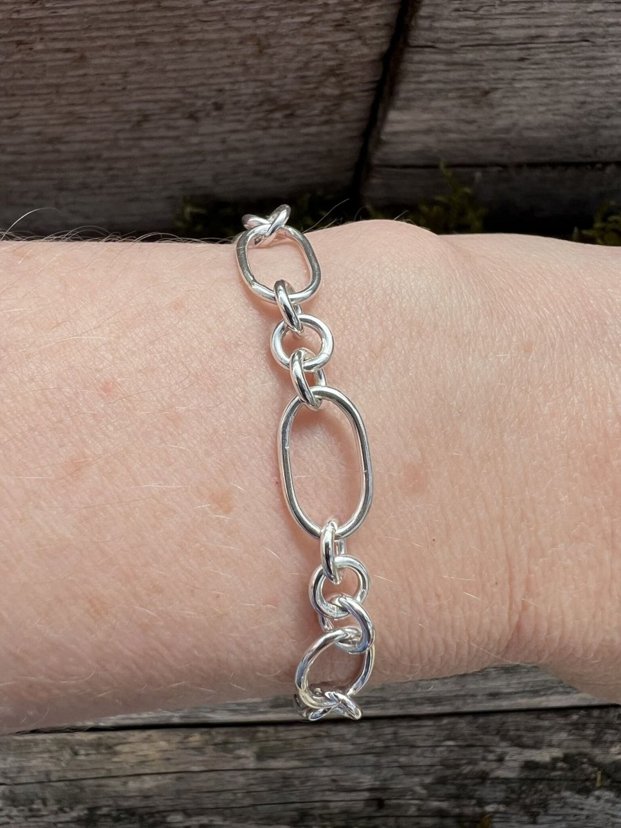 Recycled sterling silver fetter and three link bracelet worn on a wrist, showing scale and the mixed chain link pattern