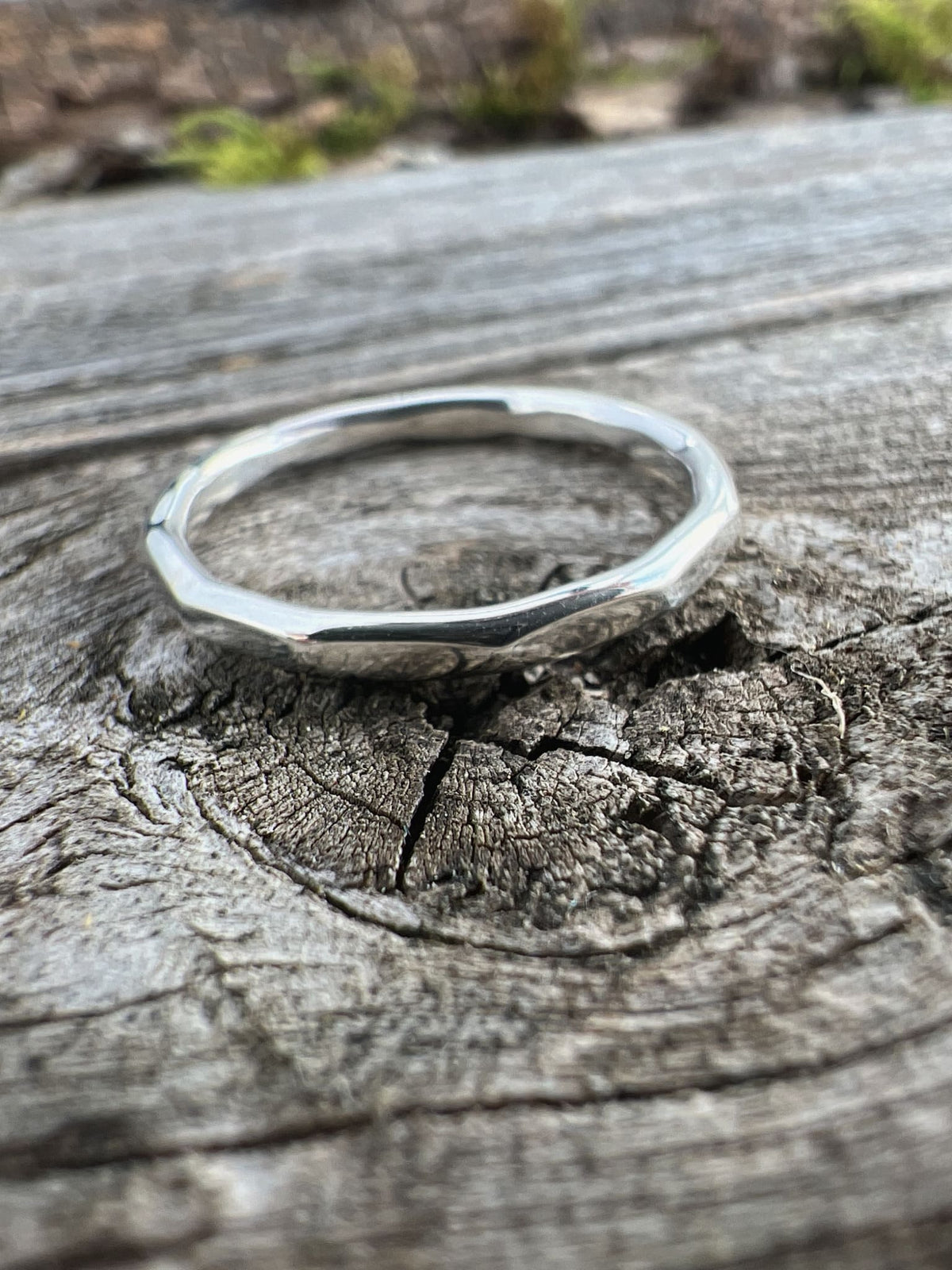 Recycled sterling silver flat hammered ring on driftwood, showing the flat band profile