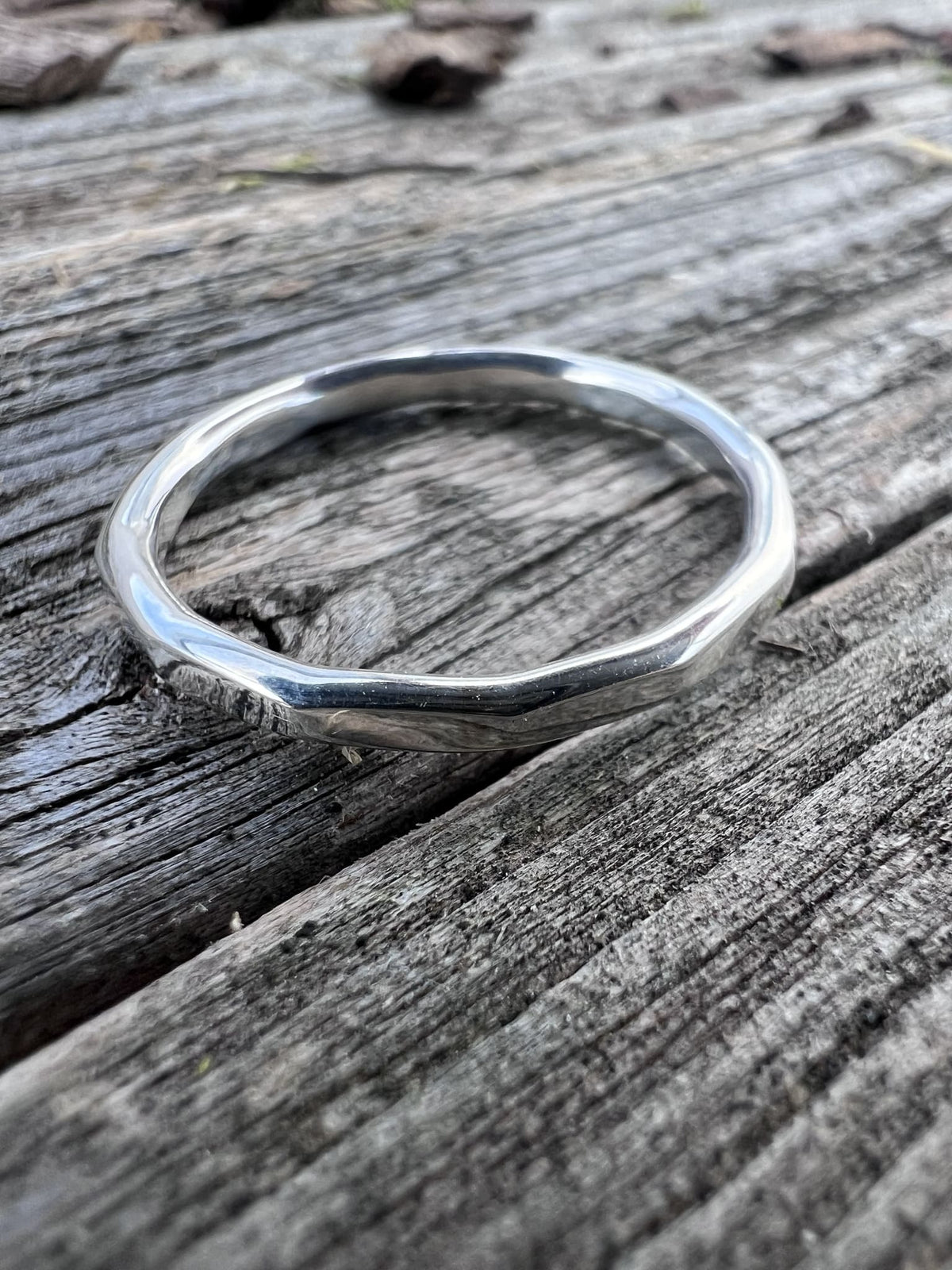 Recycled sterling silver flat hammered ring on weathered driftwood, showing the polished flat band