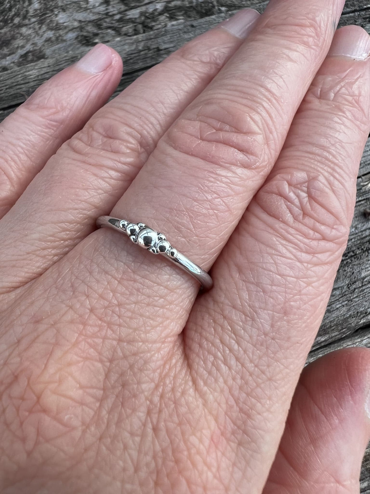 Sterling silver granule row ring worn on a finger, showing scale and the delicate row of silver granules