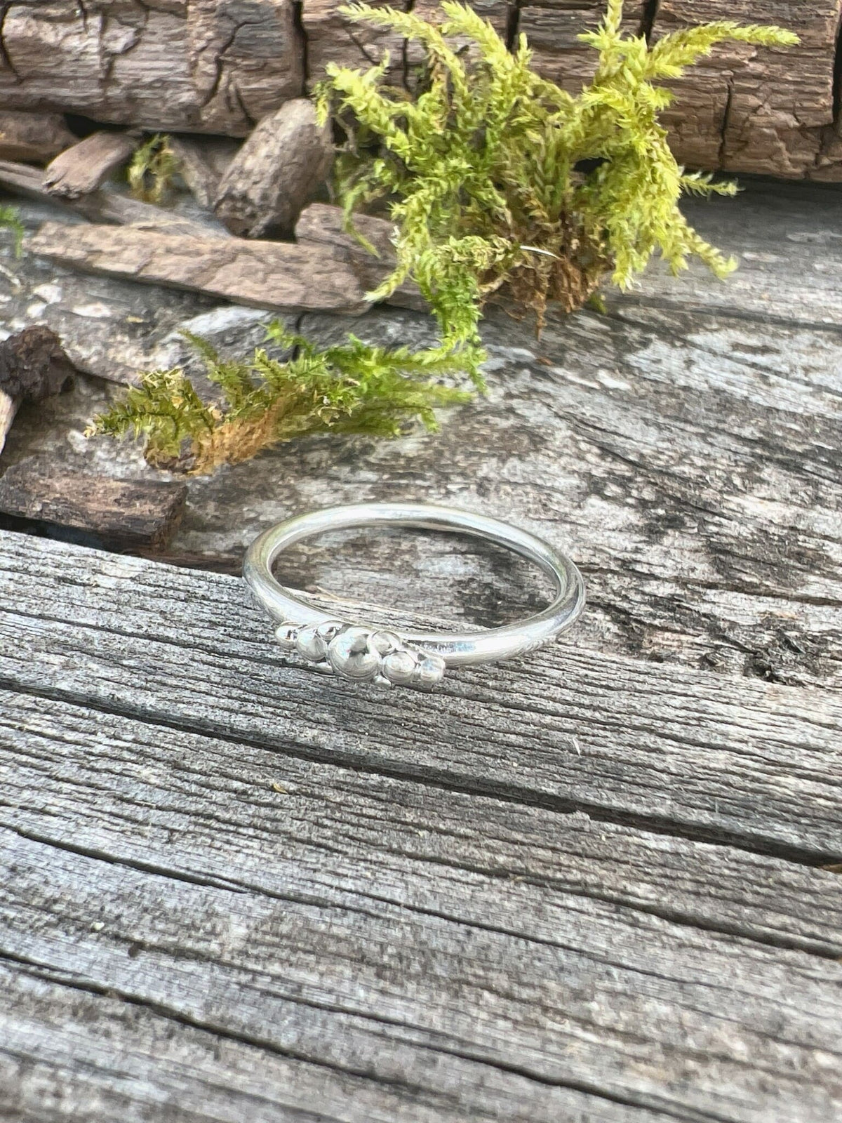 Handmade sterling silver granule row ring on driftwood, overhead view showing the full granule row from above