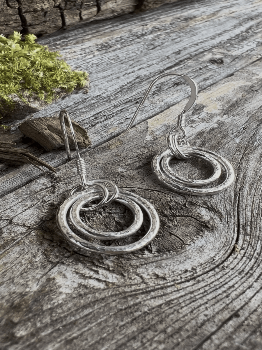 Recycled silver harmonic circles drop earrings styled on weathered wood with moss, showing the layered circle design from the front