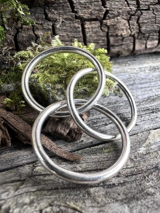 Recycled sterling silver interlinking rings on weathered wood, showing the looping open structure