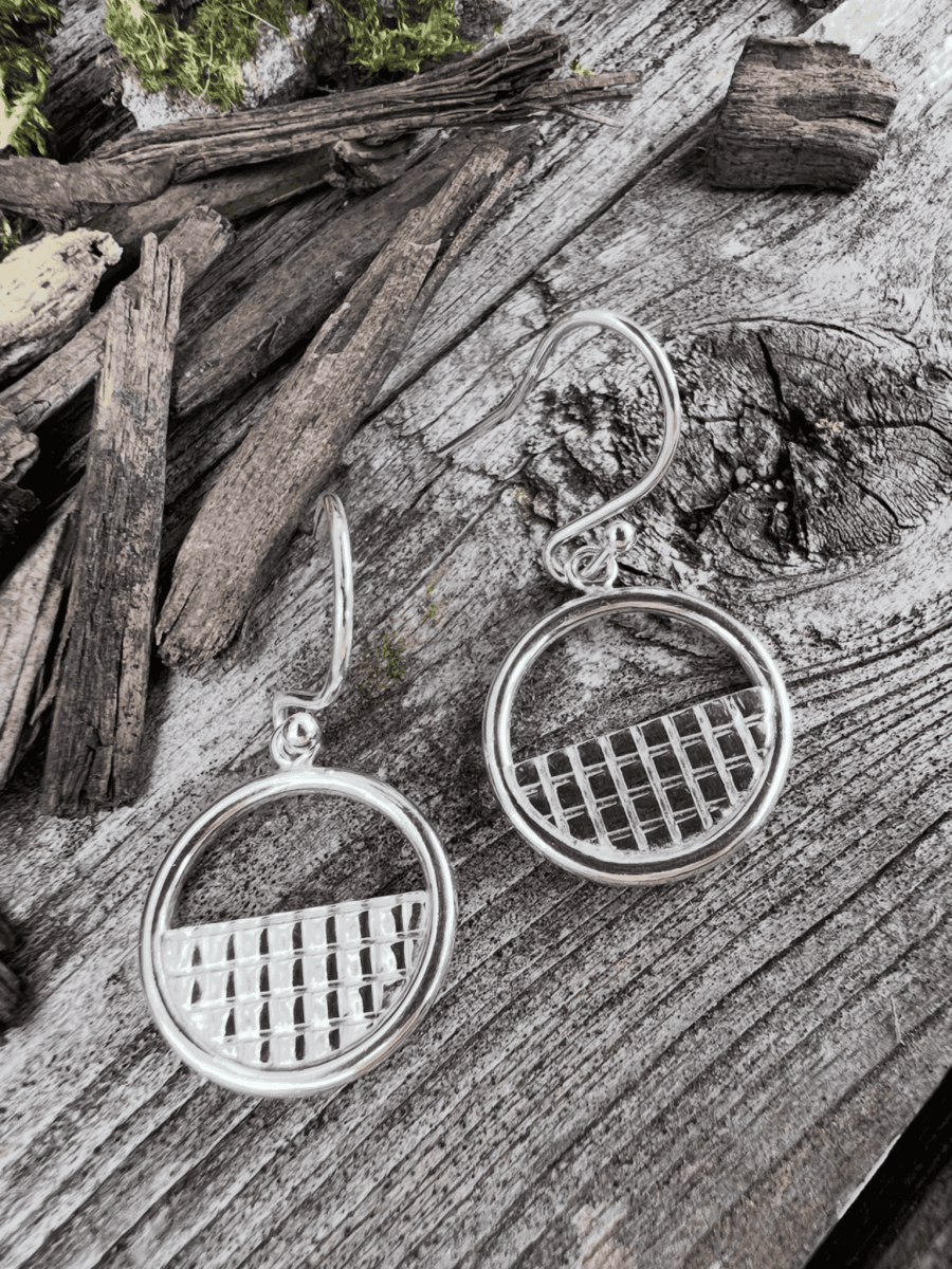 Recycled sterling silver lattice halo drop earrings on weathered wood, showing the circular halo frame with woven lattice centre