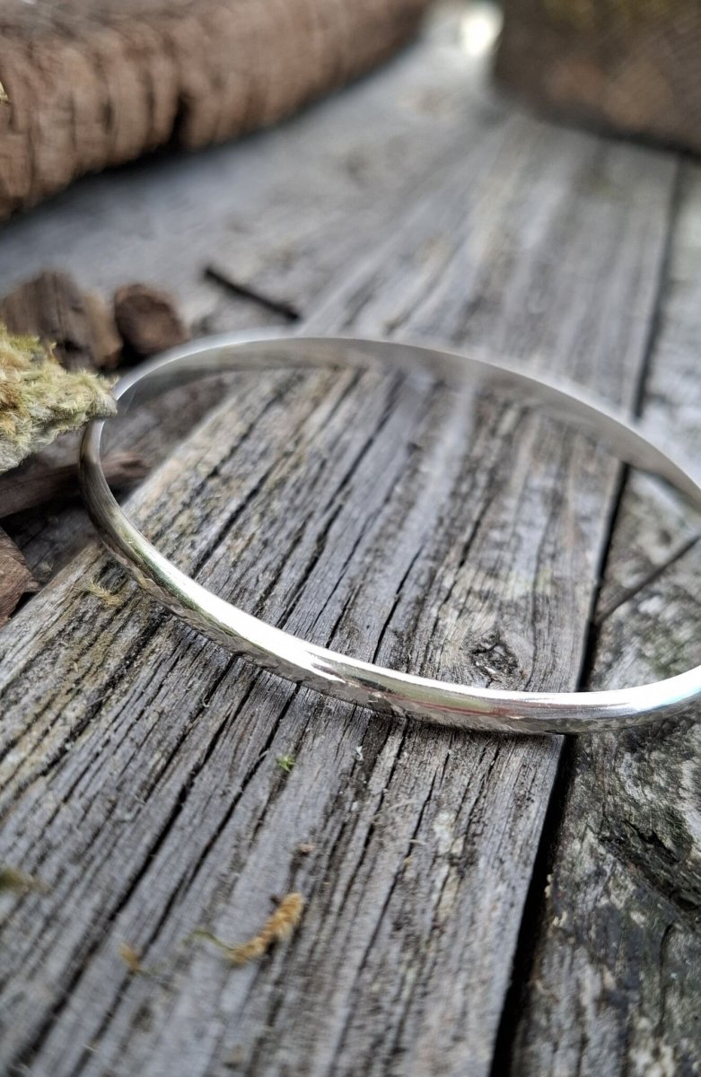 Recycled sterling silver minimal luxe bangle lying on weathered wood, minimalist handmade jewellery