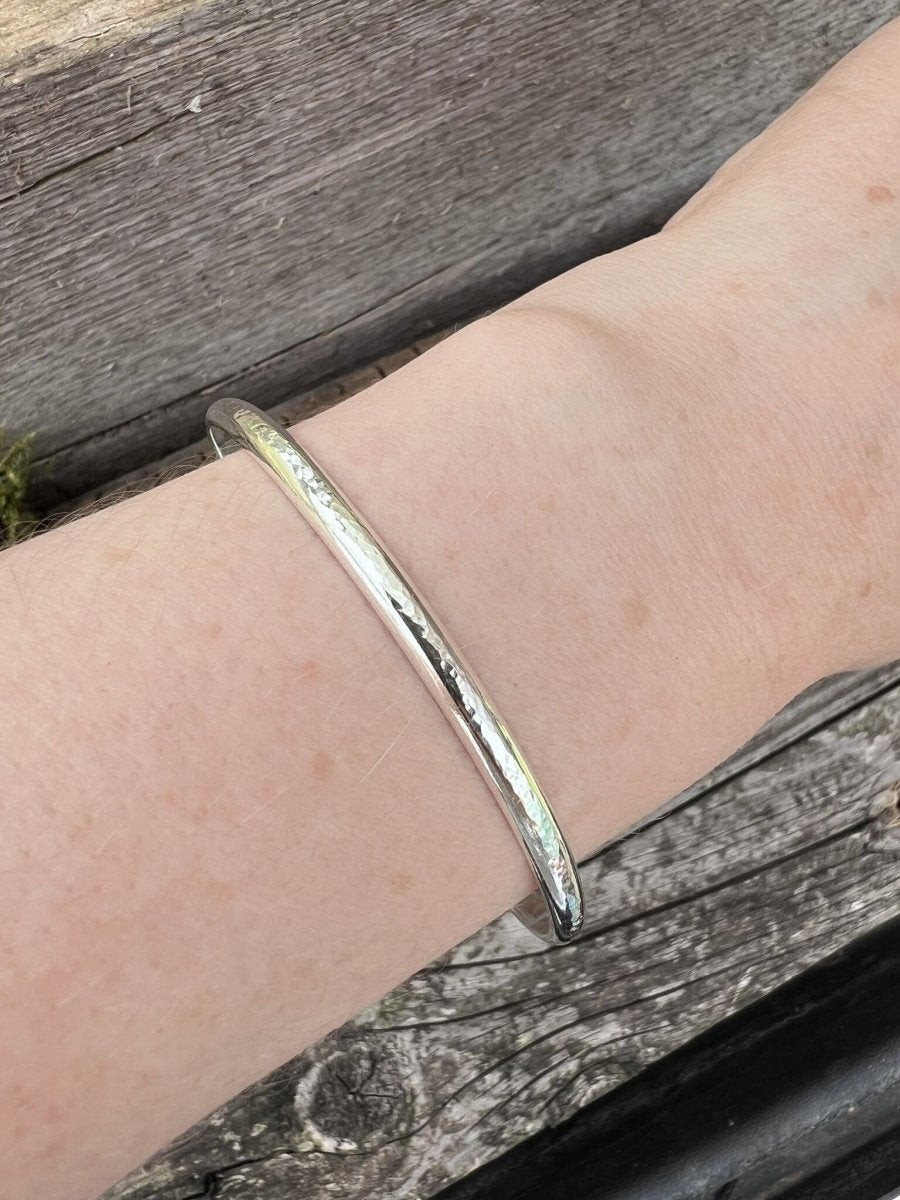 Recycled sterling silver minimal luxe bangle worn on a wrist, showing scale and the delicate fine band