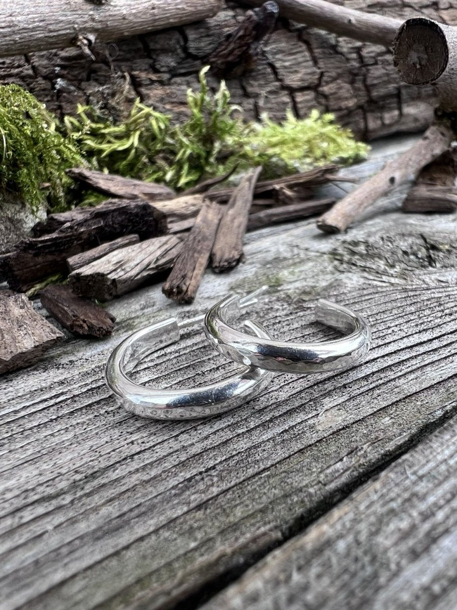Handmade sterling silver mini hoop small earrings on weathered wood, photographed from the side showing the round hoop profile