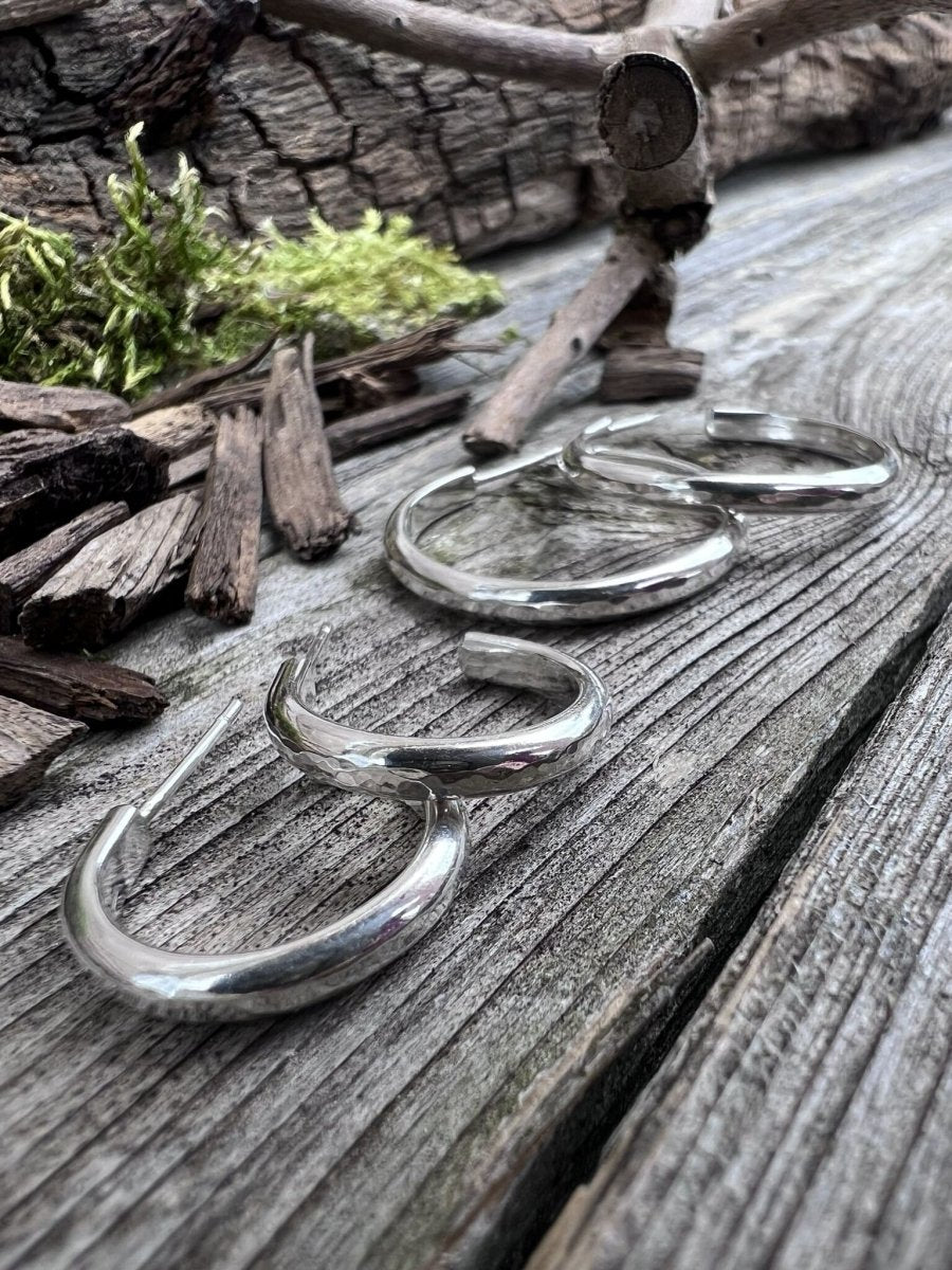 Recycled sterling silver mini luxe hoop earrings on weathered wood with moss, showing the slim polished hoop form