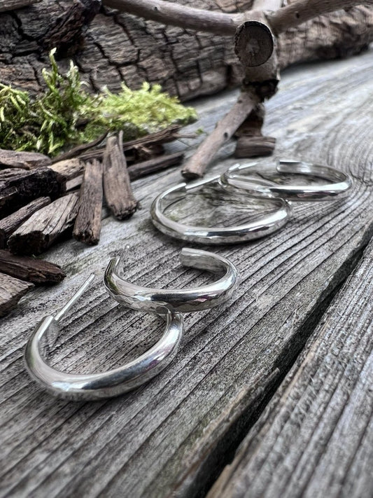 Recycled sterling silver mini luxe hoop earrings on weathered wood with moss, showing the slim polished hoop form