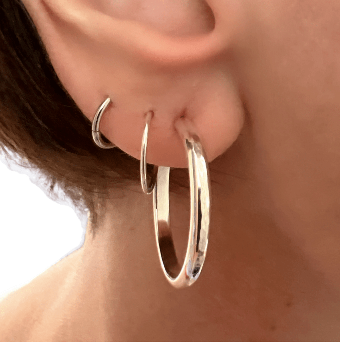 Sterling silver mini luxe hoop medium earrings worn in ear, showing scale and how the polished hoops sit close to the lobe
