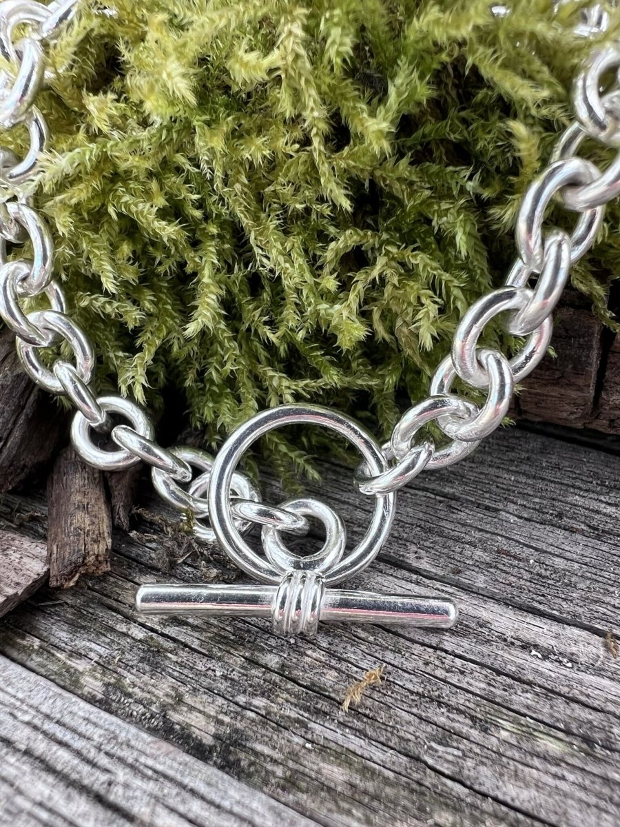 Recycled sterling silver Nova oval loop bracelet on mossy weathered wood, handmade Isle of Wight jewellery