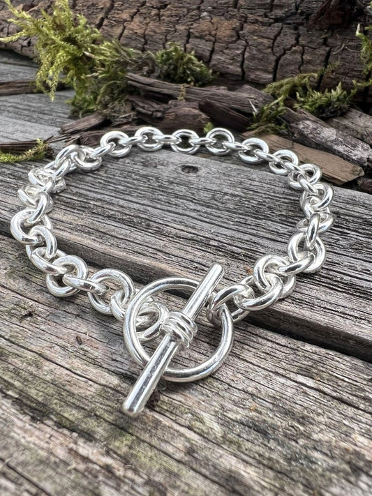 Recycled sterling silver Nova oval loop bracelet on weathered wood, showing the chunky oval links and toggle clasp