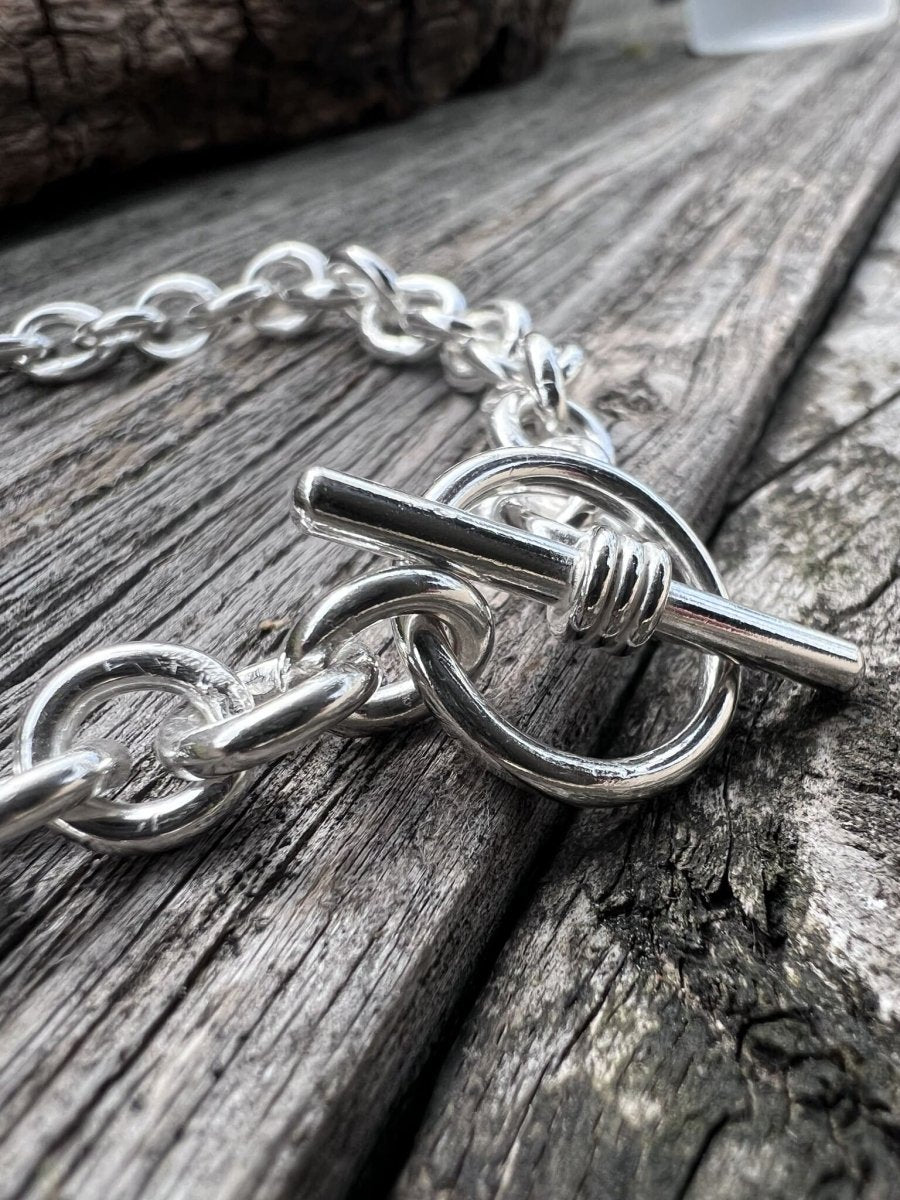 Close-up of a handmade sterling silver Nova oval loop bracelet, highlighting the large oval links and T-bar toggle clasp