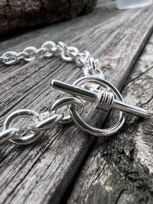 Close-up of a handmade sterling silver Nova oval loop bracelet, highlighting the large oval links and T-bar toggle clasp
