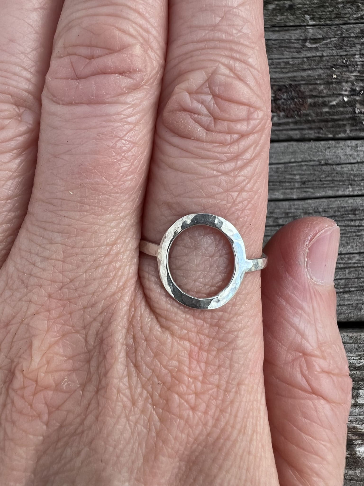 Recycled sterling silver open circle ring worn on a finger, showing how the oval frame sits on the hand