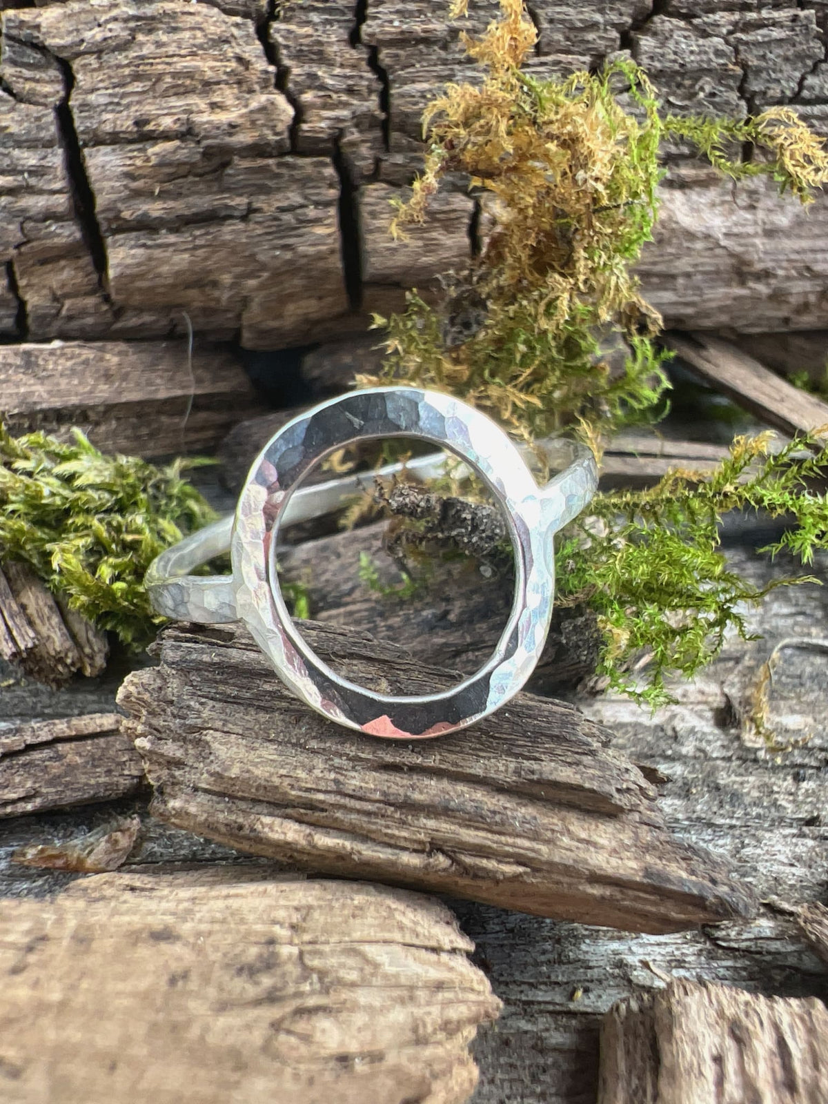 Recycled sterling silver open circle ring styled on mossy driftwood, showing the oval frame