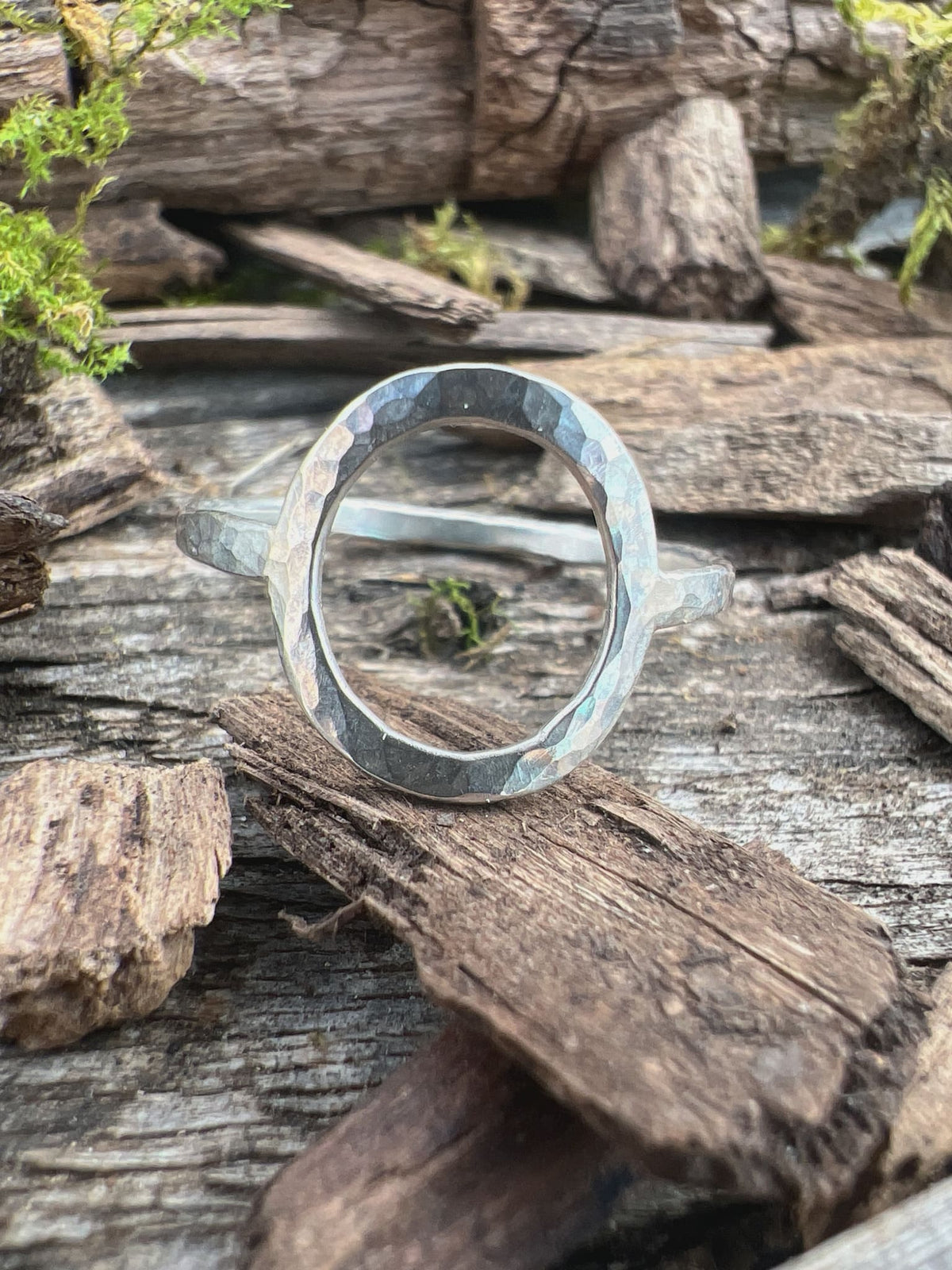 Recycled sterling silver open circle ring on weathered wood, showing the textured oval frame and open-ended band