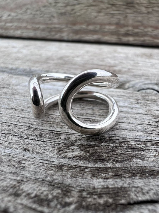 Handmade sterling silver open end loop ring styled on a rustic wooden surface, Isle of Wight jewellery