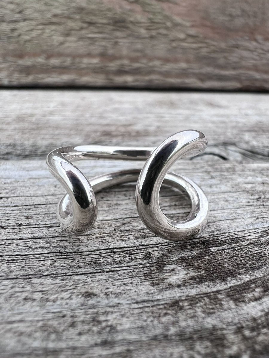 Handmade sterling silver open end loop ring styled on a rustic wooden surface, Isle of Wight jewellery