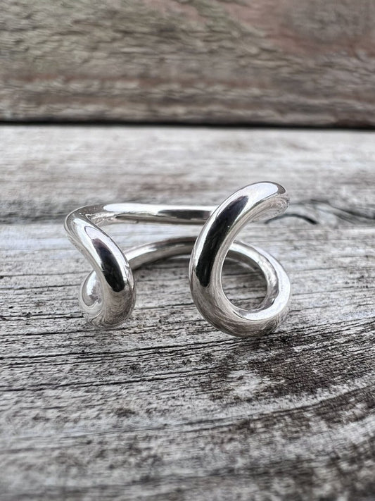 Handmade sterling silver open end loop ring styled on a rustic wooden surface, Isle of Wight jewellery