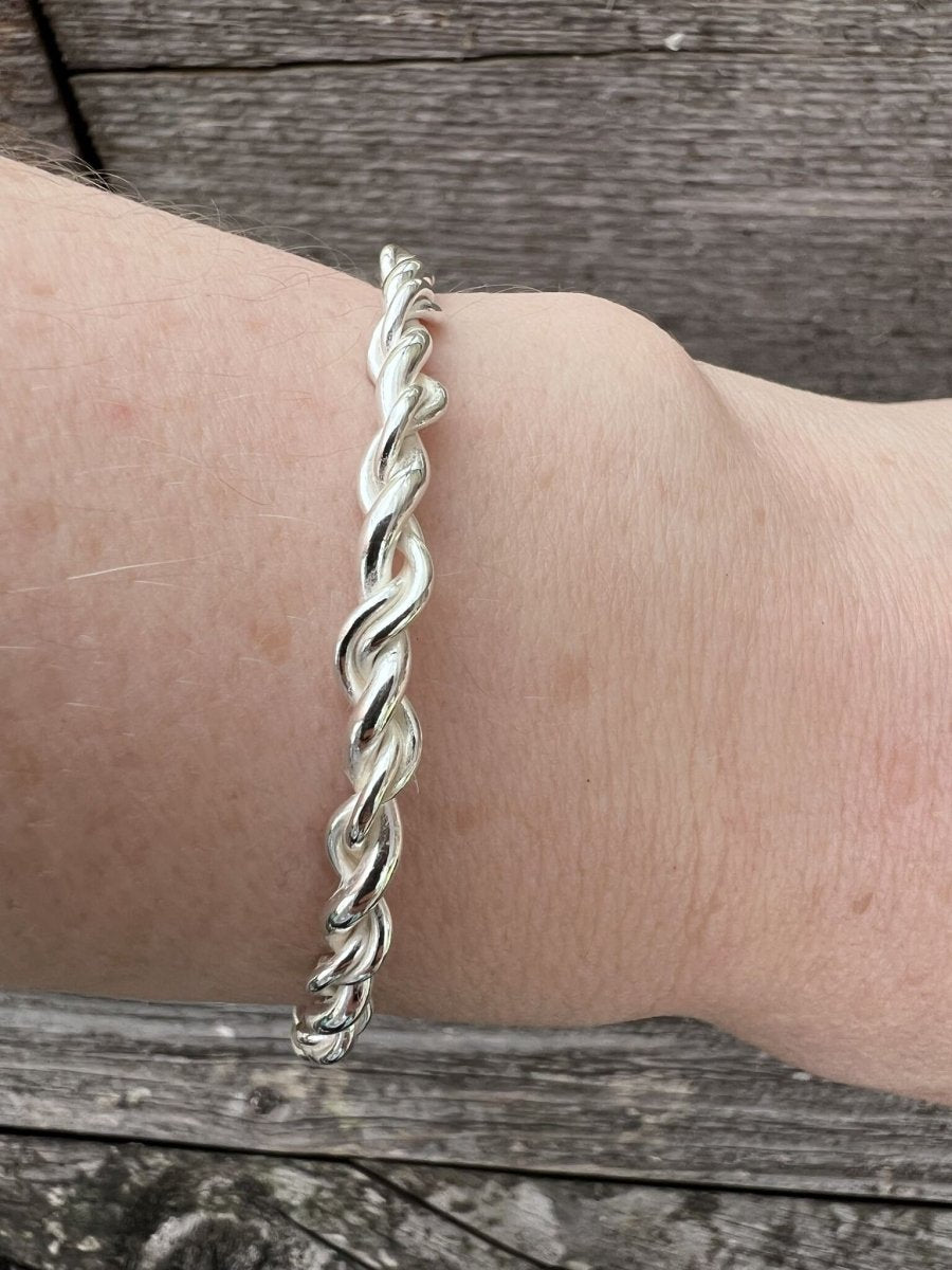 Recycled sterling silver open twist bangle worn on a wrist, showing scale and the open twisted band