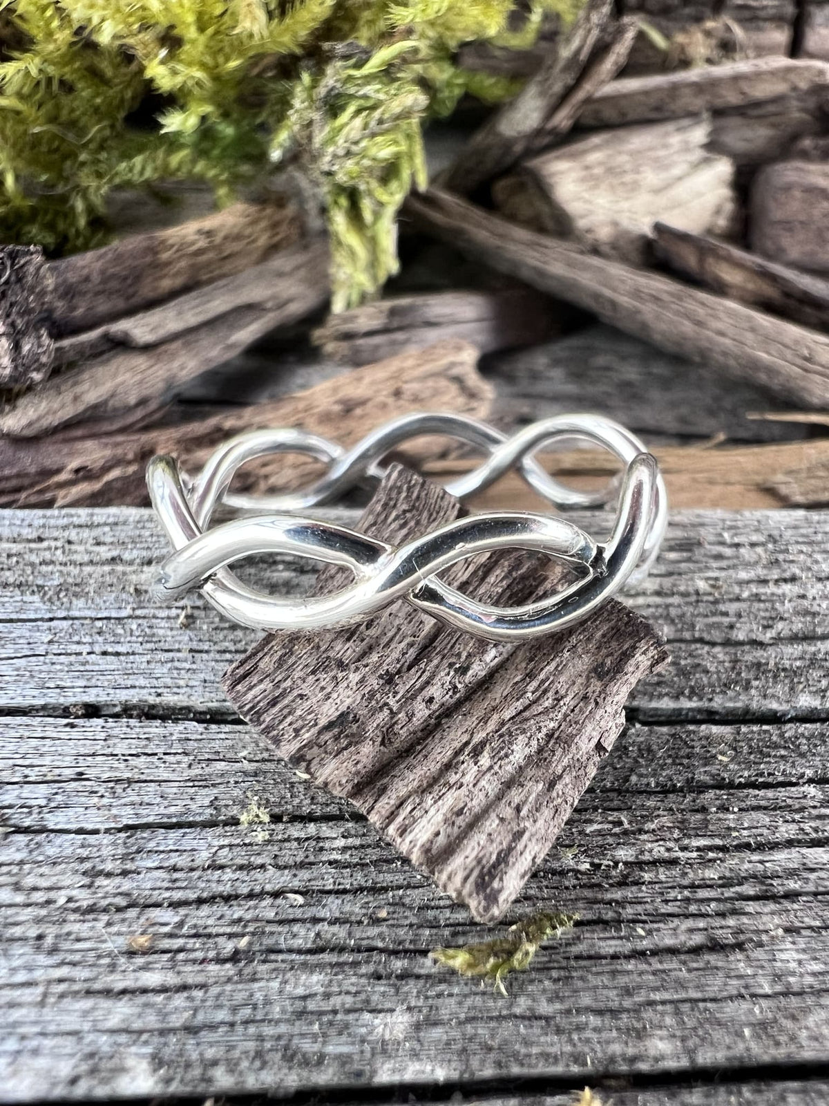Recycled sterling silver open twist ring on weathered driftwood, handmade Isle of Wight jewellery