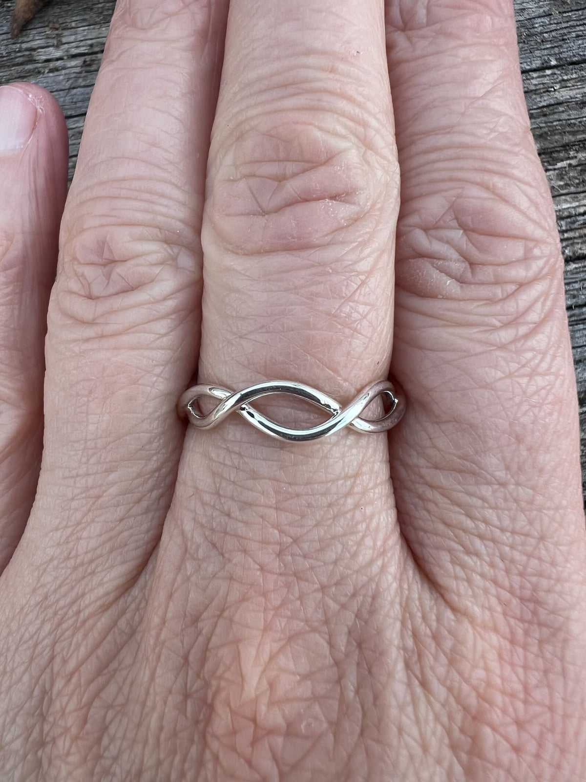 Recycled sterling silver open twist ring worn on a finger, showing the sculptural open wire twist from the front
