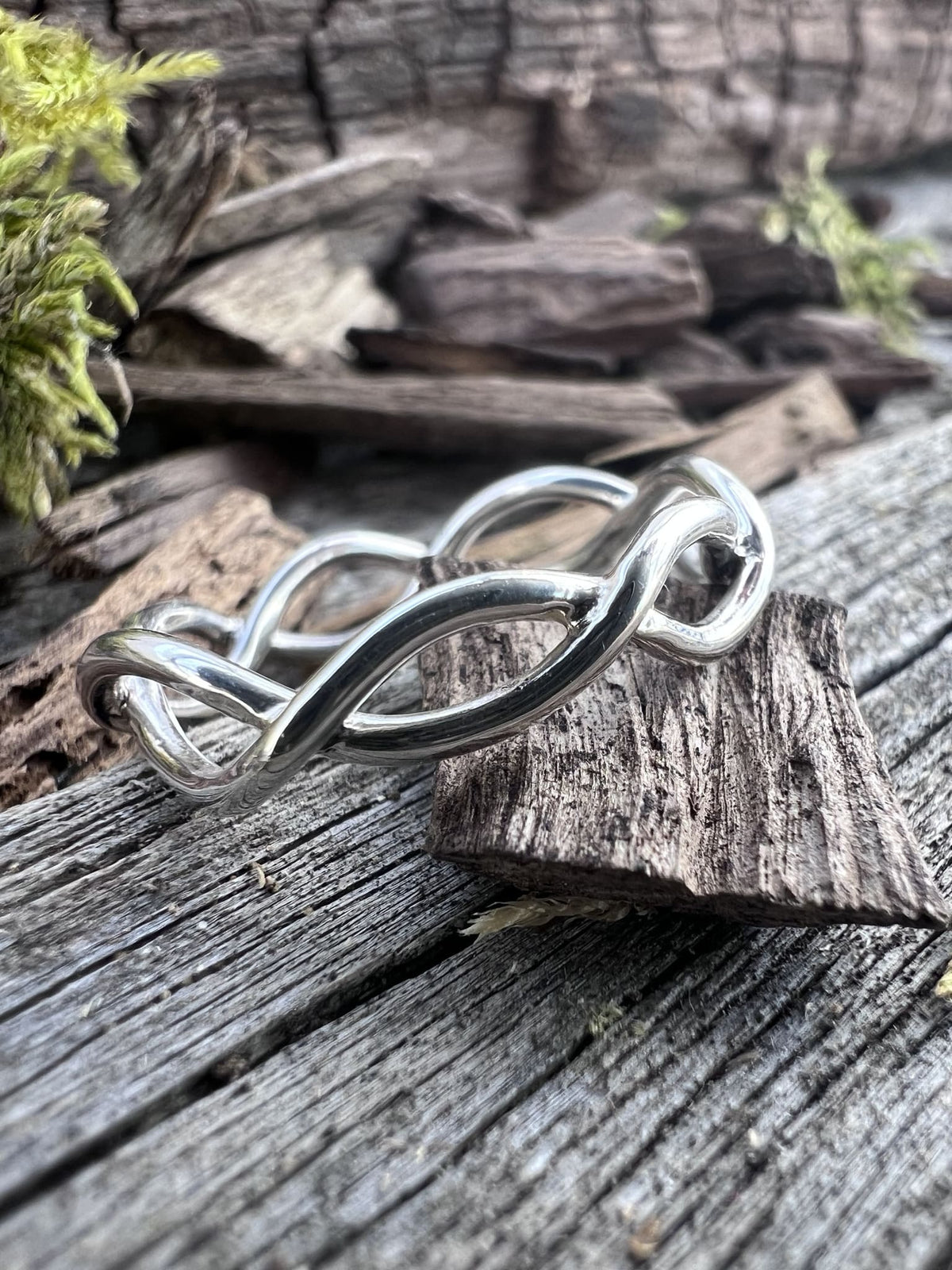Recycled sterling silver open twist ring on weathered driftwood, showing the interwoven wire twist and open form