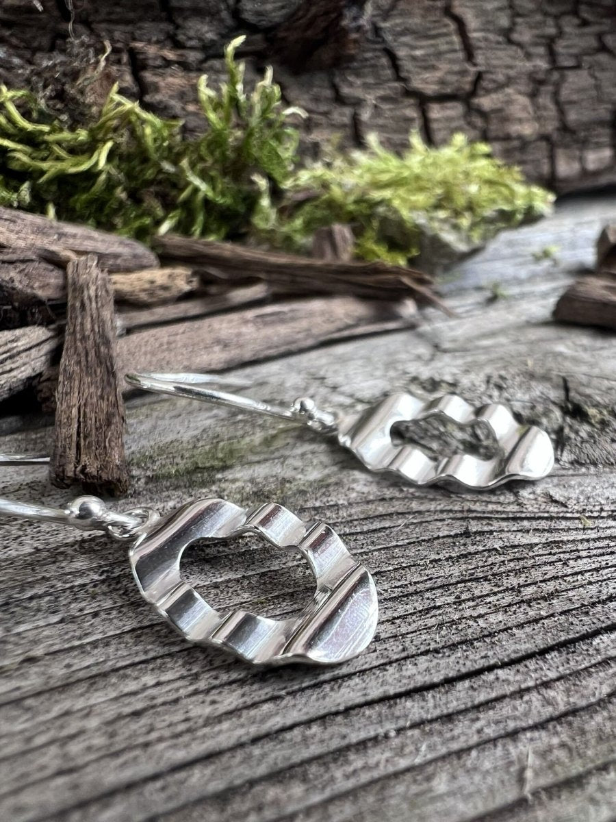 Recycled sterling silver oval wave drop earrings on weathered wood with moss, showing the undulating open oval design