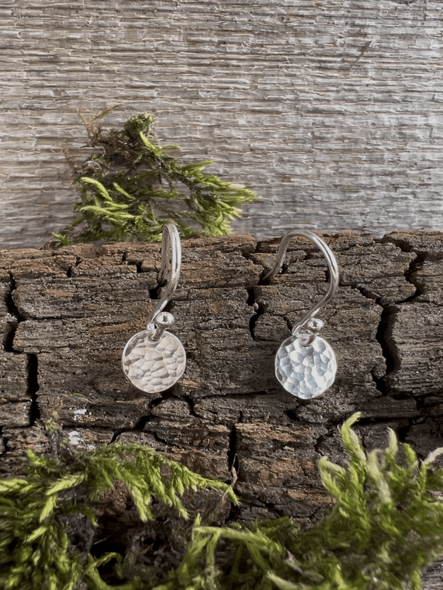 Recycled silver petite textured oval earrings styled on a textured bark background with foliage, showing the tiny pendant detail