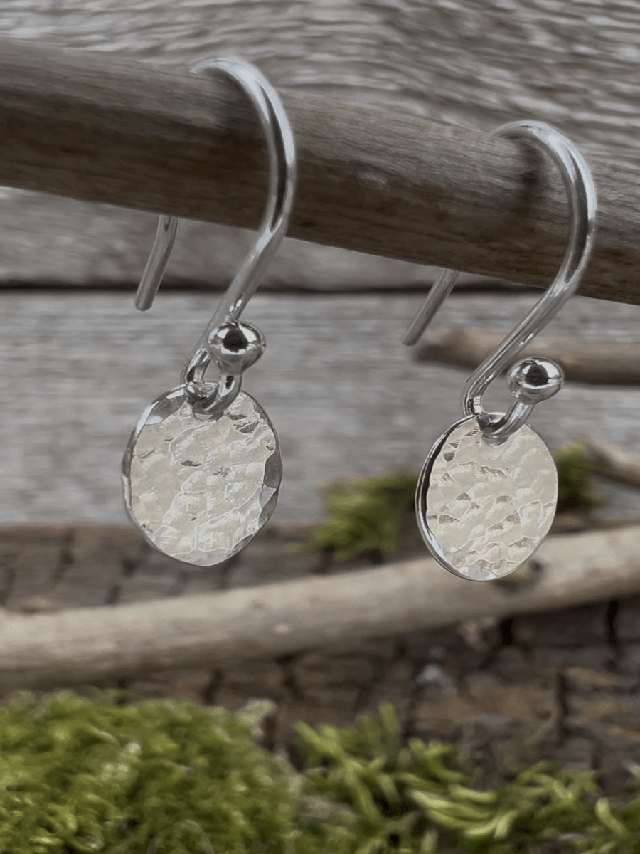 Recycled sterling silver petite textured oval drop earrings hanging from a branch, showing the small hammered oval pendant