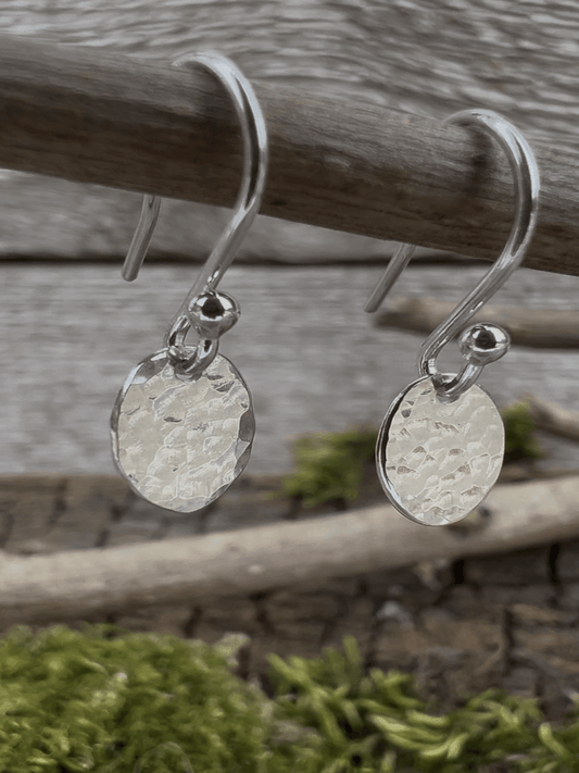 Recycled sterling silver petite textured oval drop earrings hanging from a branch, showing the small hammered oval pendant
